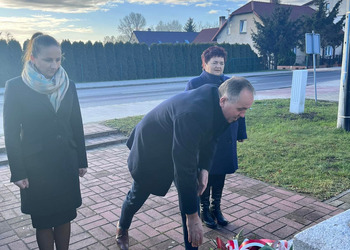 Zdjęcie przedstawia uczestników złożenia kwiatów pod pomnikiem