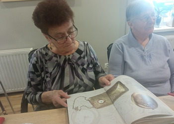 zdjęcie przedstawia seniorów podczas spotkania z antykwariuszem 