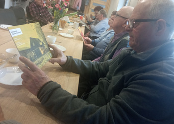zdjęcie przedstawia seniorów podczas spotkania z antykwariuszem 