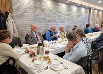 zdjęcie przedstawia seniorów zasiadających przy stole 