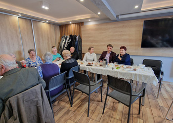 zdjęcie przedstawia seniorów zasiadających przy stole 