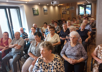 zdjęcie przedstawia grupę Seniorów słuchających wykładu