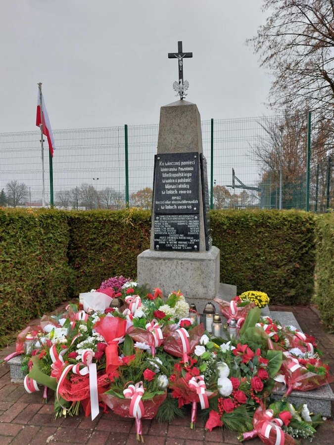 Zdjęcie przedstawia pomnik Powstańców Wielkopolskich i złożone pod nim wiązanki 